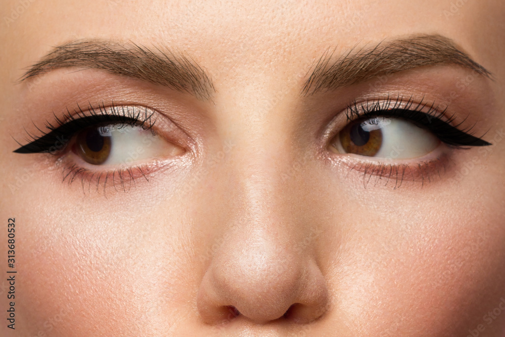 Obraz premium Cosmetics and makeup. Beautiful female eye with sexy black liner make-up. Fashion big arrow forever woman. Great evening makeup, clean makeup and brown eyes. Thick eyebrows and extra long eyelashes