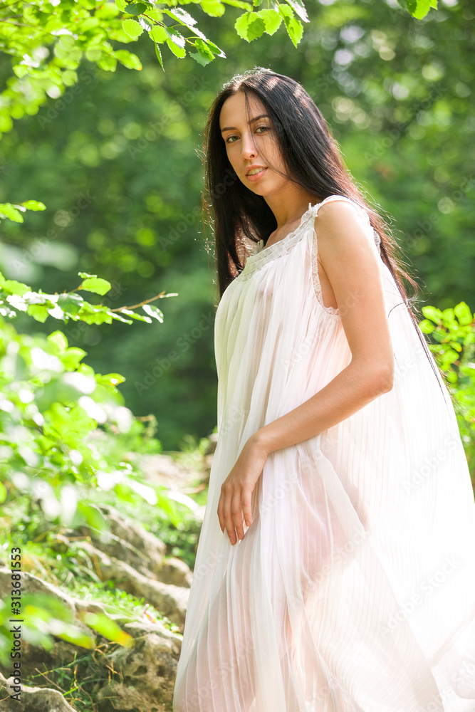 Girl with long black hair in forest. Slavic girl in a white dress. Ukrainian girl in ethnic dress. Girl with long black hair in forest. Slavic girl in a white dress. Ukrainian girl in ethnic dress.