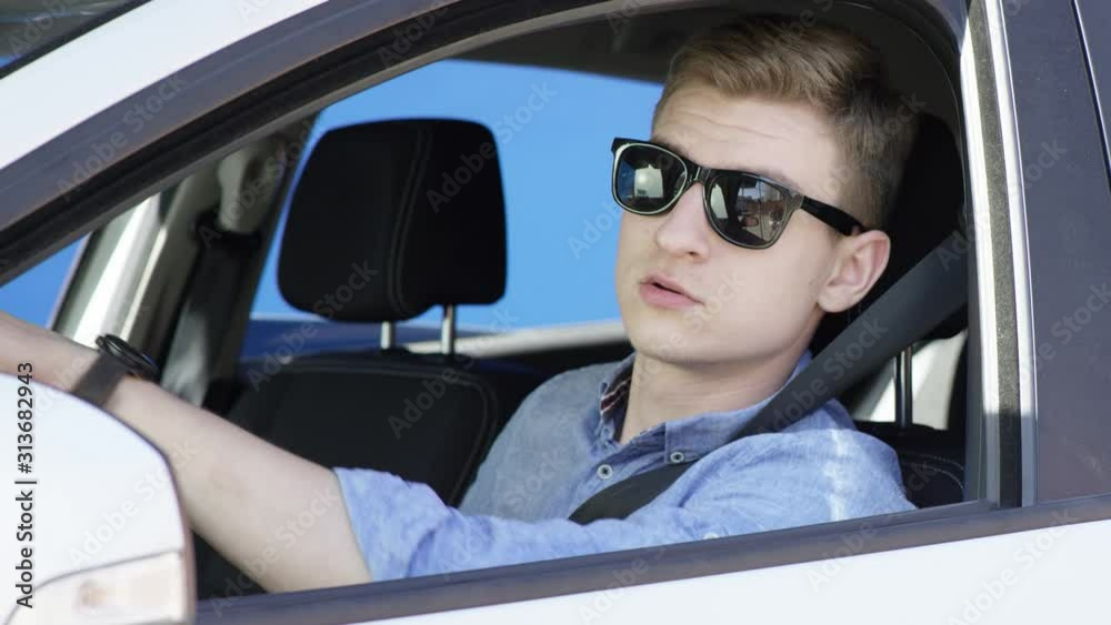 Brunette man is arguing with other drivers and pedestriants sitting in his white car with the bluesceen background. He is in casual clothes and sunglasses. Young guy is driving car with greenscreen Brunette man is arguing with other drivers and pedestriants sitting in his white car with the bluesceen background. He is in casual clothes and sunglasses. Young guy is driving car with greenscreen