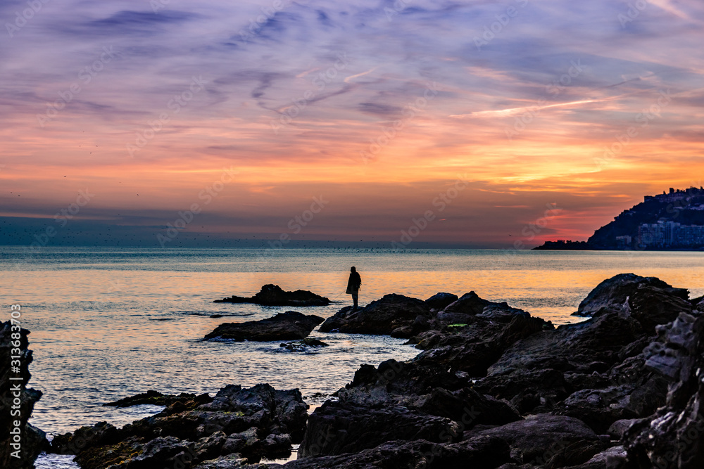 Man on rocks fishing in the sea Man on rocks fishing in the sea