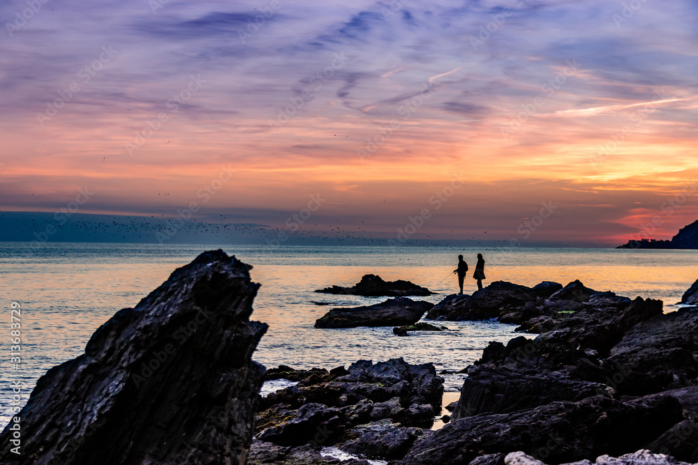 Couple on rocks fishing in the sea