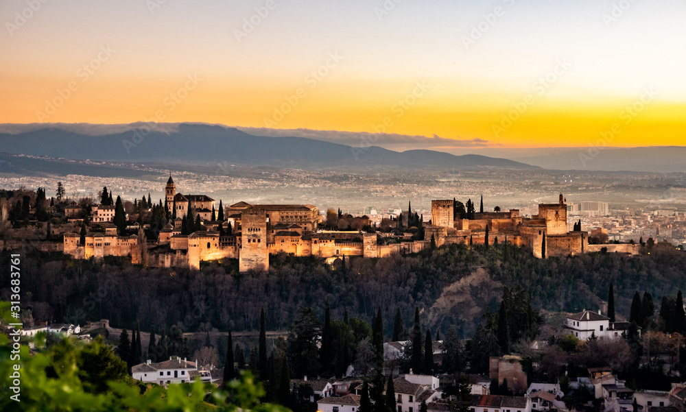 Sunset with the illuminated Alhambra in Granada and a beautiful sky