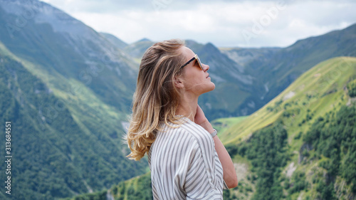 Woman hiking in mountains at sunny day time. View of Kazbegi, Georgia. Beautiful natural mountain background