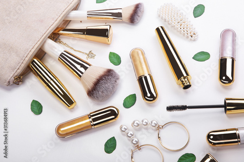 Set of brushes and cosmetic products in a cosmetic bag on a white background.