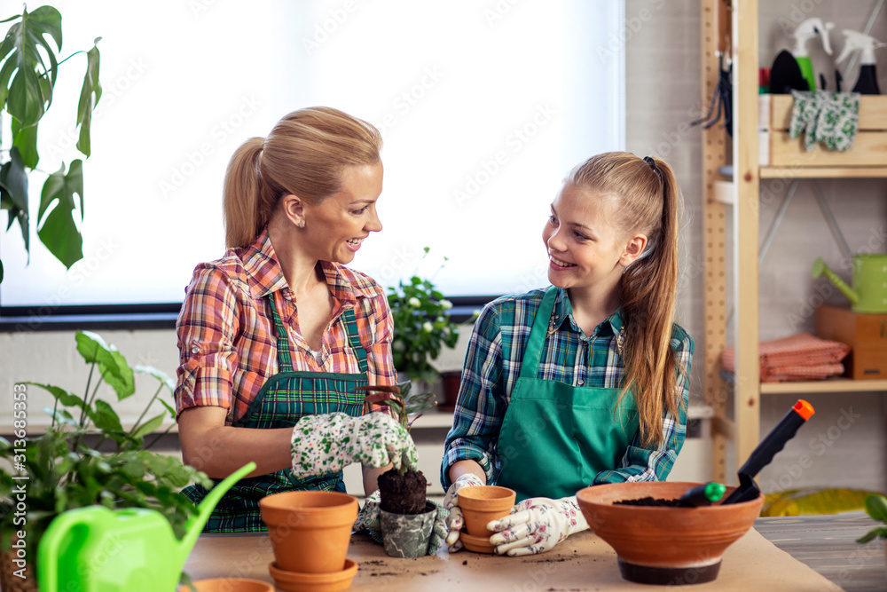 Mom and daughter plant flowers on desk at home together and feel happy