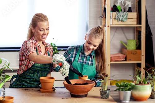 Mom and daughter plant flowers on desk at home together and feel happy © pucko_ns