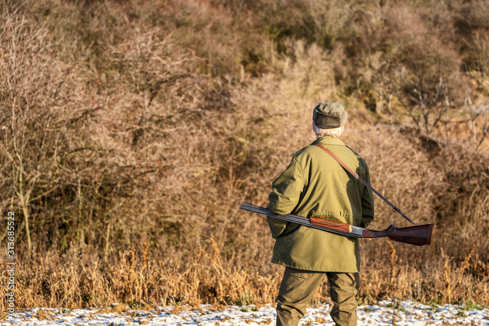 Scenic view of hunter waiting for a prey. Gamekeeper walks over field.