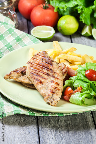 Grilled chicken breasts served with fries