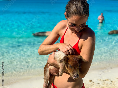 Schöne junge Frau streichelt Baby Schwein auf den Bahamas, Exuma.
