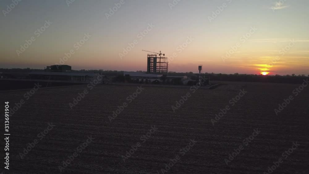 the construction of a skyscraper under construction with a tower crane against the background of an orange sky with the setting sun. Romantic landscape of a natural phenomenon.Building the construction of a skyscraper under construction with a tower crane against the background of an orange sky with the setting sun. Romantic landscape of a natural phenomenon.Building
