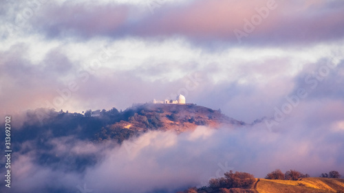 Storm clouds covering the top of Mount Hamilton, with Lick Observatory peeking through them; San Jose, South San Francisco Bay Area, California photo