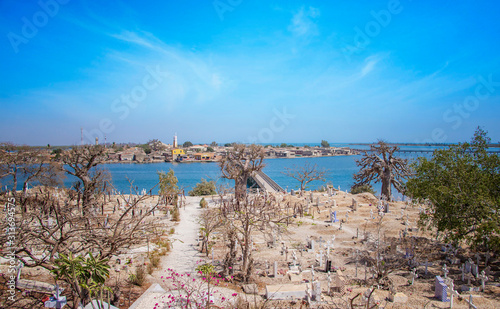 View from the hill on the island Joal-Fadiout, Senegal. Baobab trees on the Christian cemetery in Africa. There is town and long wooden bridge. photo