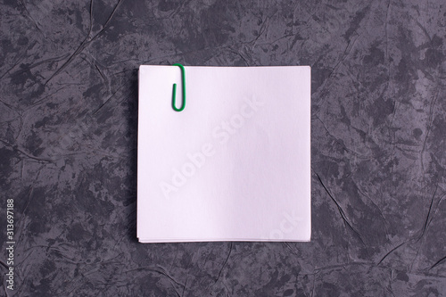 A sheet of white paper with a paper clip on a gray background.