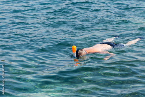 Man swimming in blue shallow sea. Snorkeling full-face snorkeling mask. Active seaside vacation. Water sport in sea.