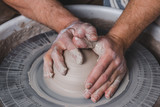 Potter making a new vase of white clay on the potter's wheel circle in studio, concept of manual work, creativity and art, horizontal photo