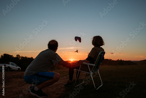 people watching a paragliding at sunset