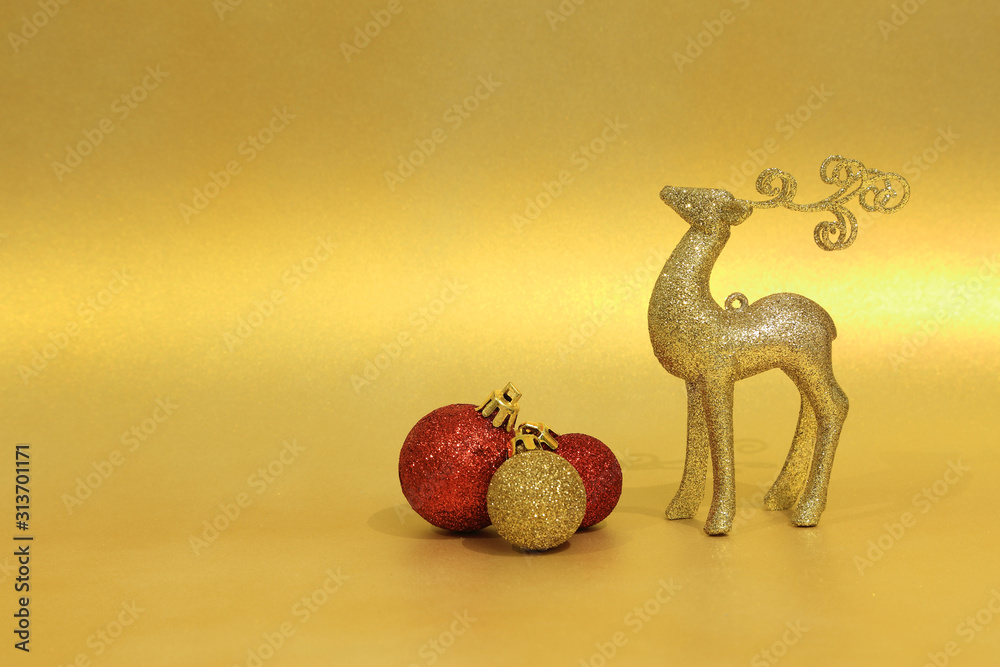 Figurka złotego jeloneka i bombki choinkowe na złotym tle, Boże Narodzenie. - obrazy, fototapety, plakaty 