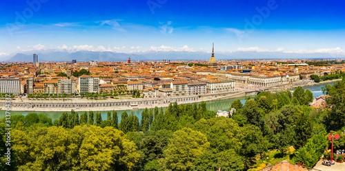 Aerial PAnoramic summer view on Turin skyline, with the city center, Po river, Mole Antonelliana, modern skyscrapers and other landmark seen from viewpoint the Monte dei Cappuccini on snowy alps Italy