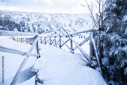 zimowy most drewniany w górach pokryty lodem i śniegiem