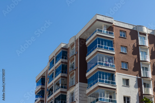 an outdoor perspective shoot to corner of a modern building with brown and white colors - clean blue background