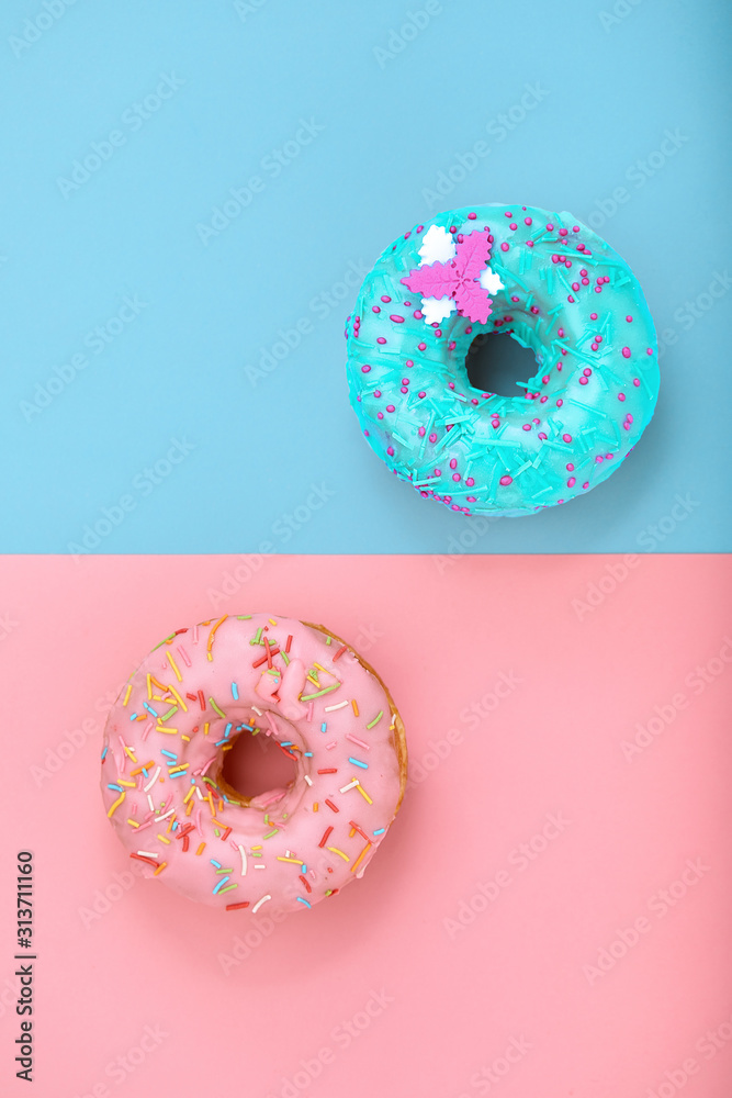 Two donuts on pastel pink and blue background. Minimalism creative food composition. Flat lay style Two donuts on pastel pink and blue background. Minimalism creative food composition. Flat lay style