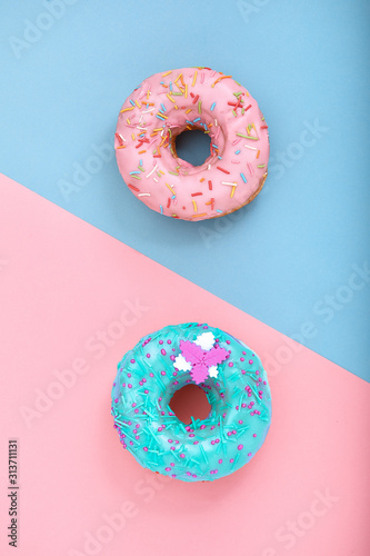 Two donuts on pastel pink and blue background. Minimalism creative food composition. Flat lay style
