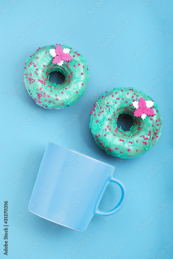 Blue Donuts with icing and coffe cup on pastel blue background. Sweet donuts.