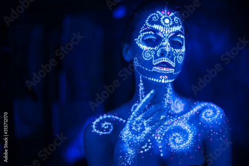 Schilderij op canvas Body art on the body and hand of a girl glowing in the ultraviolet light