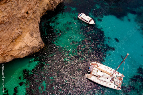 A catamaran and a snorkel boat anchor in the Clear Mediterranean waters of the Blue Lagoon.
