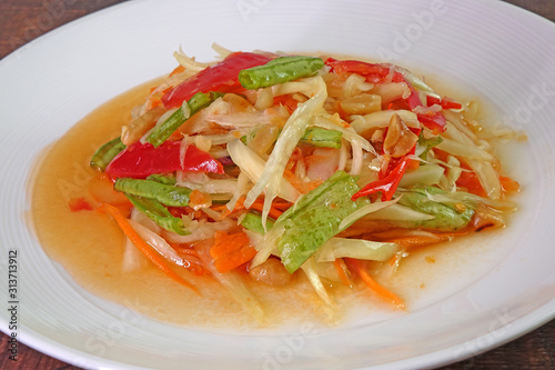 Somtam or Spicy green papaya salad, Thai cuisine. Green papaya salad is a spicy salad made from shredded unripe papaya. Originating from ethnic Lao people, it is also eaten throughout Southeast Asia.