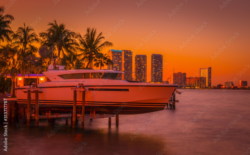 Fototapeta premium sunset orange miami florida beach buildings sea sky palm tropical boat traveling ocean vacation island landscape luxury