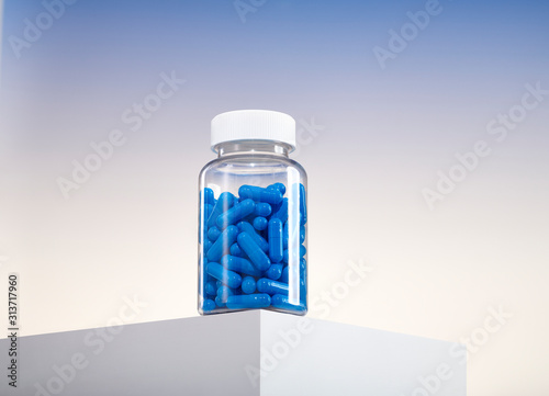 Bottle of Blue Color Pills Capsule Medication Vitamins on Counter Table Edge 