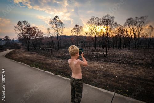 Young boy taking photos of aftermath of the 2019/2020 bushfire season in New South Wales, Australia