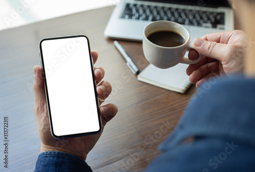 Mockup image blank white screen cell phone.man hand holding texting using mobile on desk at office.background empty space for advertise text.people contact marketing business,technology 