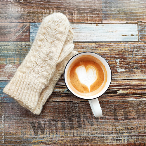 Winter background with cup of coffee and woollen mittens. Cup of coffee with heart
