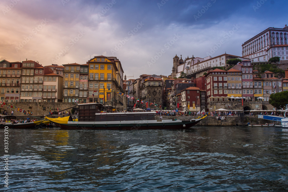 Oporto, Portugal - Douro river with boat and city skyline with colorful houses at summer sunset