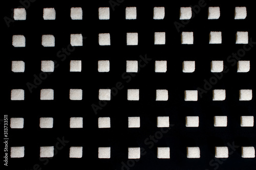 background from sugar cubes on a black background  white sugar create a uniform pattern on a black background