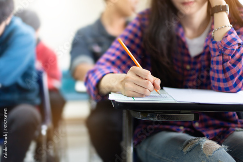 high school,university student study.hands holding pencil writing paper answer sheet.sitting lecture chair taking final exam attending in examination classroom.concept scholarship for education abroad