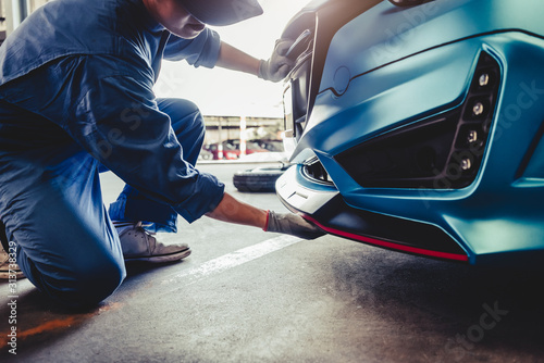 Mechanics installing front skirt at auto repair shop garage. Transportation and Business concept. Automobile technician maintenance vehicle by customer claim order. Car salon accessories decoration photo