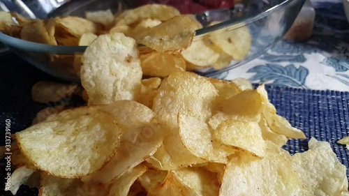 Crispy thin sliced kettle fried salted Potato chips falling down in slow motion on dinner table cloth, balsamic vinegar snack. photo