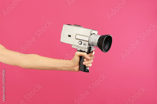 Woman with vintage video camera on crimson background, closeup of hand photo