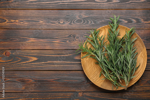 Bunch of fresh rosemary on wooden table, top view. Space for text