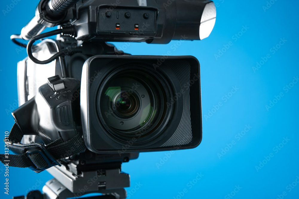 Professional video camera on blue background, closeup