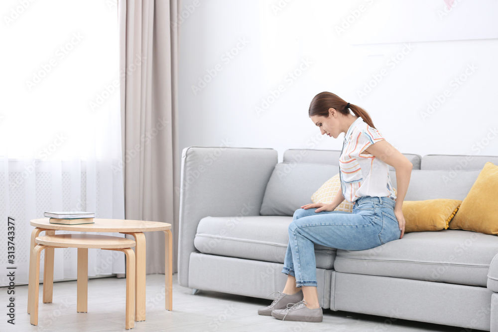 Young woman suffering from hemorrhoid on sofa at home Young woman suffering from hemorrhoid on sofa at home