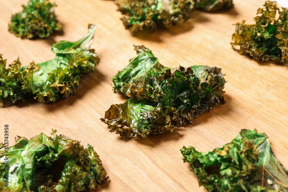 Tasty baked kale chips on wooden table, closeup Tasty baked kale chips on wooden table, closeup