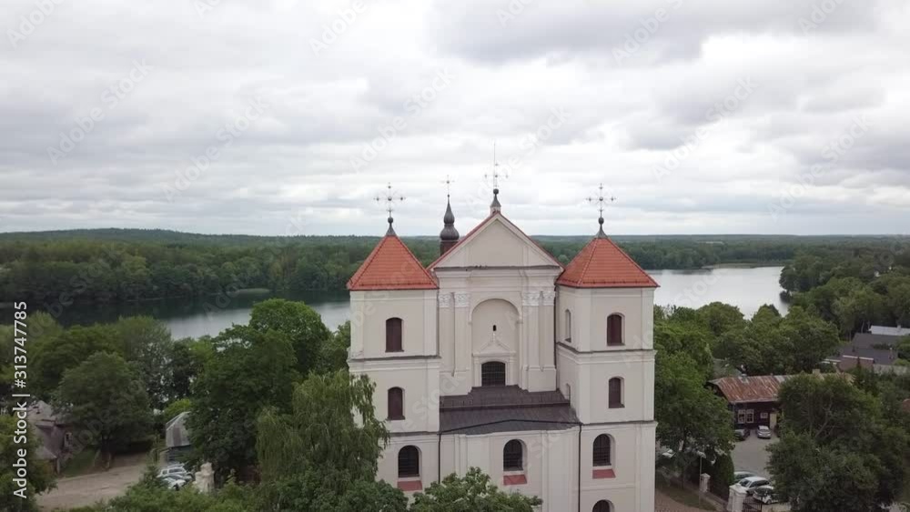 High angle aerial view of the white church covering forest and lake background, slow movement High angle aerial view of the white church covering forest and lake background, slow movement