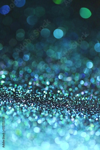 Blue glitter with green bokeh on a black background. Turquoise glitter brilliant mockup.  background with twinkle lights.blue shiny  glitter layout.