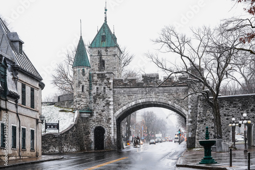 Landscape view of Porte Saint Louis gate on the fortified wall with street during blizzard in winter season photo