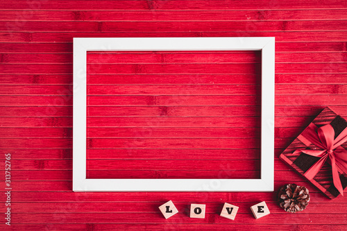 Wallpaper Mural Happy Valentines Day with Empty white Photo Frame, LOVE Cube Boxes, Gift, Pine Cone on Red Wooden Table in Backgroundd Torontodigital.ca