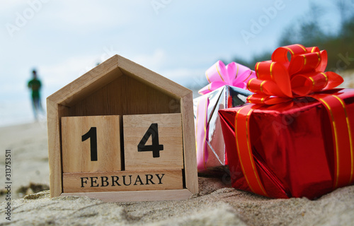 Happy Valentines day concept, Wooden calendar on February 14, red gift box in soft focus background.